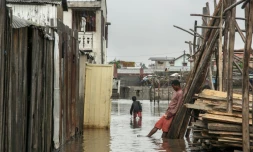 Des habitants marchent dans l'eau qui a inondé le quartier d'Antohomadinika, à Antananarivo, le 24 janvier 2022, après le passage de la tempête tropicale Ana