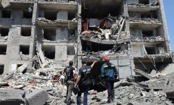 Un procureur pour crimes de guerre, un sauveteur et un civil, près d'un bâtiment détruit après avoir été touché par une frappe de missile dans la ville ukrainienne de Serhiivka, près d'Odessa, tuant au moins 18 personnes et en blessant 30, le 1er juillet 2022