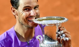 L'Espagnol Rafael Nadal mord son trophée du Masters 1000 de Rome aprÚs sa victoire en finale sur le Serbe Novak Djokovic, le 16 mai 2021