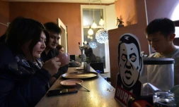 Des consommateurs boivent une boisson au café Kommouna à Bichkek, le 5 décembre 20190 devant un dessin représentant Rayimbek Matraimov, un symbole de la corruption au Kirghiztan