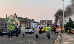 Un feu allumé par des manifestants prÚs de la mosquée de Southport en Angleterre, gardée par des policiers, le le 30 juillet 2024 au lendemain d'une attaque meurtriÚre contre des enfants