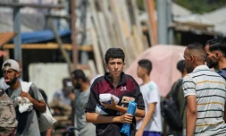 Des déplacés palestiniens portent des produits alimentaires obtenus à un point de distribution du centre de la bande de Gaza, le 26 juillet 2025