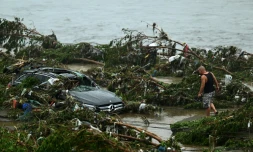 Un homme regarde une voiture endommagée suite à de fortes pluies dans le district de Fangshan à Pékin, le 1er août 2023