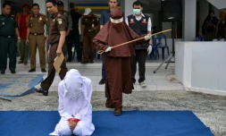 Une éxécutrice sur le point de flageller en public une femme agenouillée, le 10 décembre 2019 à Aceh, en Indonésie