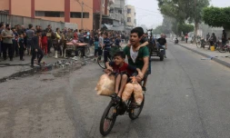 Des jeunes portent des sacs de pain sur du vélo à Rafah, dans le sud de la bande de Gaza, le 28 octobre 2023