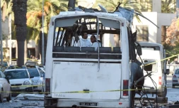 Des enquêteurs de la police scientifique relèvent des indices sur la carcasse d'un bus de la sécurité présidentielle cible d'un attentat à la bombe en plein centre de Tunis, le 25 novembre 2015