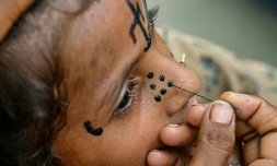 Un tatouage traditionnel est dessiné sur le visage de la jeune Champa, 7 ans, à la colonie Jogi à Umerkot, un district à majorité hindoue, le 14 juillet 2025 au Pakistan