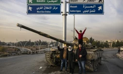 Des Syriens posent devant un tank détruit à Damas, après la prise de la capitale par les rebelles, le 12 décembre 2024