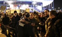 Un policier devant un cordon de sécurité derrière lequel des supporteurs de l'équipe de France de foot attendent après une série d'explosions au Stade de France, le 13 novembre 2015 à Saint-Denis, près de Paris