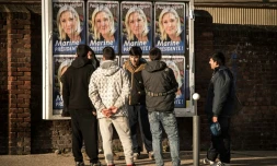 Des migrants regardent les panneaux électoraux à Calais avec en affiche la tête de liste FN de la région Nord, Marine Le Pen, le 7 décembre 2015