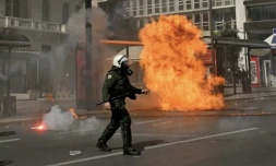 Un policier passe à proximité d'un cocktail molotov lors de heurts en marge d'une manifestation, le 5 mars 2023 à Athènes ( AFP / Louisa GOULIAMAKI )