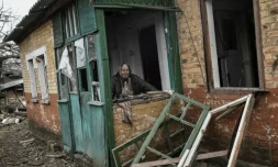 Une femme ĂągĂ©e derriĂšre une fenĂȘtre de sa maison endommagĂ©e par un bombardement Ă Tchassiv Iar, prĂšs de Bakhmout, le 11 mars 2023 ( AFP / Aris Messinis )
