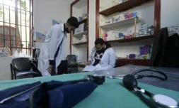 Deux étudiants en médecine regardent un livre d'allemand, dans un dispensaire à Damas le 21 janvier 2023 ( AFP / LOUAI BESHARA )