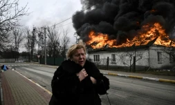 Une femme passe devant une maison en flammes après avoir été bombardée dans la ville d'Irpin