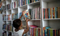 Un jeune garçon replace un livre sur une étagère de la bibliothèque "Mundo da Lua" à Rio de Janeiro