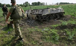 Un soldat ukrainien passe à proximité d'un char russe détruit dans un champ au sud de la ville de Mykolaiv (Ukraine) le 12 juin 2022