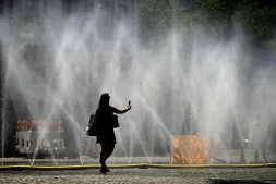 Une femme prend une photo de tuyaux d'arrosage déversant de l'eau pour apporter un peu de fraîcheur face à la chaleur estivale, à Cologne, dans l'ouest de l'Allemagne, le 25 juin 2026