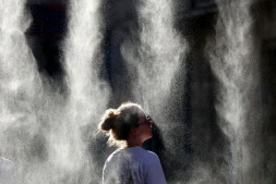Une femme se rafraîchit sous un brumisateur à l'occasion de la Fête de la Musique à Bordeaux, en Gironde, pendant un épisode de canicule en France, le 21 juin 2026