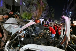 Des passants et des secouristes inspectent la carcasse du minibus dans lequel une bombe a explosé, à Jaramana, près de la capitale syrienne, Damas, le 6 août 2026