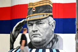 Un homme passe devant une fresque murale représentant l'ancien chef militaire des Serbes de Bosnie, Ratko Mladić, le 6 septembre 2026 à Belgrade, en Serbie, dont l'inhumation est prévue le 7 septembre 2026 au cimetière de Topčider à Belgrade, sur fond de critiques de l'UE concernant la "glorification" d'un criminel de guerre condamné pour génocide