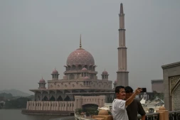 Deux personnes se prennent en photo devant une mosquée dans un air saturé par des fumées toxiques, à Putrajaya, en Malaisie, le 17 octobre 2026