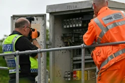 Un membre de la police des transports britannique photographie l'intérieur d'un boîtier de localisation (LOC) en bordure de voie, près du site d'une collision entre deux trains de l'East Midlands Railway (EMR) survenue la veille, le 20 juin 2026 au sud de Bedford, dans le centre de l'Angleterre