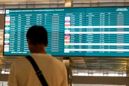 Un passager bloqué à l'aéroport international Soekarno-Hatta en raison de l'éruption du volcan Anak Krakatau, regarde un écran d'information sur les vols, le 7 septembre 2026 à Tangerang, en Indonésie