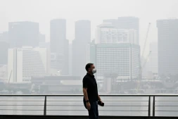 Un passant porte un masque de protection le long du boulevard à Marina Bay, noyé dans la brume, le 12 octobre 2026 à Singapour
