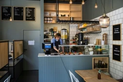 Kajetan Grzelczak derrière son comptoir  au café Andon à Stockholm, entièrement dirigé par l'IA, le 27 avril 2026