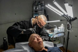 Remy, tatoueur professionnel, réalise une intervention de micropigmentation du cuir chevelu sur un client, dans son studio de Ginowan, à Okinawa au Japon, le 19 mai 2026