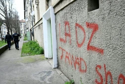 Des policiers patrouillent à proximité d'un mur avec un tag DZ désignant la DZ mafia à Avignon le 13 mars 2025