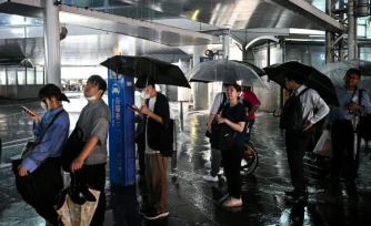 Des personnes attendent un taxi à la station de métro de Chiba, dans la ville de Chiba à l'est de Tokyo, le 13 août 2026, alors que de fortes pluies s'abattent sur la région