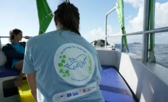 Un scientifique porte un t-shirt à l'effigie des dugongs, lors d'une collecte d'ADN pour la conservation du mammifÚre marin, dans l'océan Indien, le 22 mai 2026 au nord de Mayotte ( AFP / Marine GACHET )