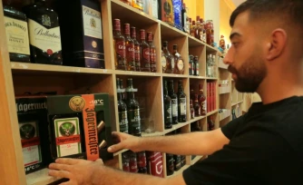 Un commerçant dispose des bouteilles d'alcool dans sa boutique de Qamichli, ville kurde du  nord-est de la Syrie, le 18 août 2026