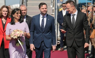 Le vice-président américain JD Vance (c) et sa femme, Usha Vance, accueillis par le ministre hongrois des Affaires étrangères, Peter Szijjarto, le 7 avril 2026 à Budapest, en Hongrie