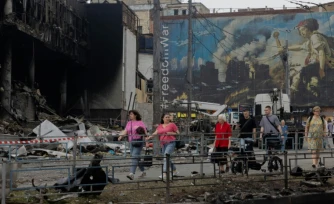 Des habitants passent devant un centre commercial endommagé à la suite des frappes russes à Kiev, le 25 mai 2026