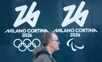 Une personne passe devant les logos des Jeux olympiques et paralympiques d'hiver de Milan Cortina, à Milan, le 5 février 2026