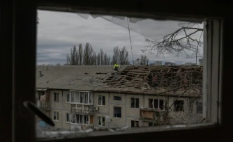 Des ouvriers dégagent les débris du toit d'un immeuble résidentiel fortement endommagé après une frappe de drone russe à Kyiv, le 23 décembre 2025 en Ukraine