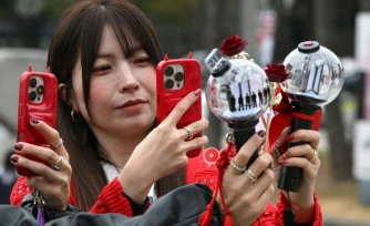 Des fans prennent des photos de bâtons lumineux à l'effigie de BTS à leur arrivée au stade où le groupe de K-pop se produira, à Goyang, le 9 avril 2026
