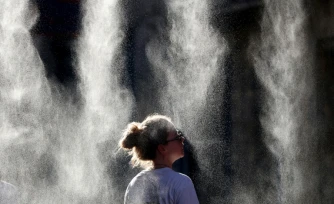 Une femme se rafraĂźchit sous un brumisateur Ă l'occasion de la FĂȘte de la Musique Ă Bordeaux, en Gironde, pendant un Ă©pisode de canicule en France, le 21 juin 2026