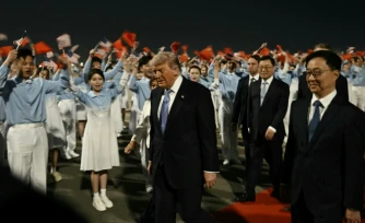Le président américain Donald Trump (c) accompagné par le vice-président chinois Han Zheng (d) à son arrivée à l'aéroport international de Pékin, le 13 mai 2026