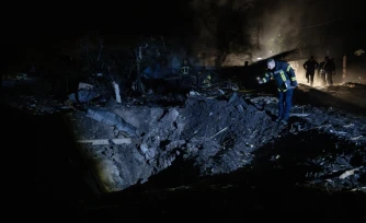 Un pompier ukrainien examine un cratÚre aprÚs une frappe de missile russe qui a touché des habitations à Kiev dans la soirée du 21 octobre 2026
