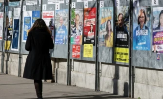 Une femme passe devant un panneau électoral avec les candidats à la mairie de Paris, le 9 mars 2026, à Paris