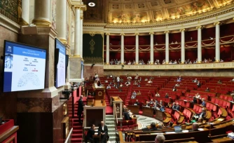 Un écran affiche l'adoption par les députés du premier article de la loi sur la protection de l'enfance et la lutte contre la violence dans les écoles à l'Assemblée nationale, le 1er juin 2026 à Paris
