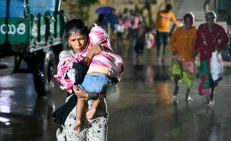 Une femme, un enfant dans les bras, se dirige vers un abri Ă l'approche du cyclone Arnab, le 27 octobre 2026 Ă Kakinada, dans l'Etat de l'Andhra Pradesh, en Inde