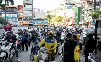 Des motocyclistes font la queue pour faire le plein d'essence dans une station-service à Hanoï, le 10 mars 2026 au Vietnam
