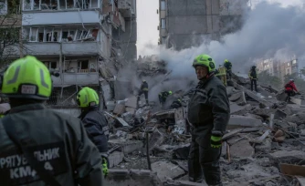 Les secouristes dans les ruines d'un immeuble détruit par une frappe russe à Kiev, le 14 mai 2026