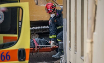 Des secouristes transportent le corps d'une personne retrouvée sous les décombres après l'effondrement d'un immeuble à Athènes, le 26 septembre 2026 
