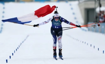 Julia Simon franchit en tête la ligne d'arrivée du relais féminin, remporté par la France le 18 février aux JO de Milan Cortina.