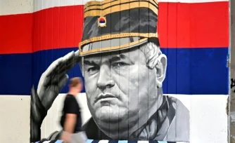 Un homme passe devant une fresque murale reprĂ©sentant l'ancien chef militaire des Serbes de Bosnie, Ratko MladiÄ, le 6 septembre 2026 Ă Belgrade, en Serbie, dont l'inhumation est prĂ©vue le 7 septembre 2026 au cimetiĂšre de TopÄider Ă Belgrade, sur fond de critiques de l'UE concernant la "glorification" d'un criminel de guerre condamnĂ© pour gĂ©nocide